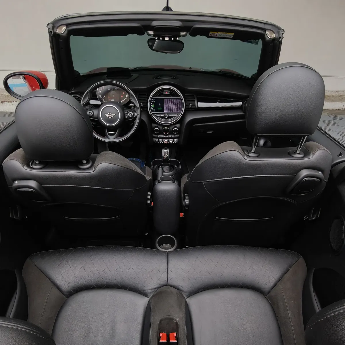 Vista aérea interior desde la parte trasera de un Mini Cooper S Convertible Hot Chili 2021 seminuevo con asientos traseros de piel negros en Namacar Automotriz.