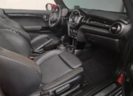 Vista lateral izquierda del habitáculo interior de un Mini Cooper S Convertible Hot Chili 2021 seminuevo, mostrando los asientos deportivos de piel negros y el tablero de instrumentos con la capota abierta, en Namacar Automotriz.