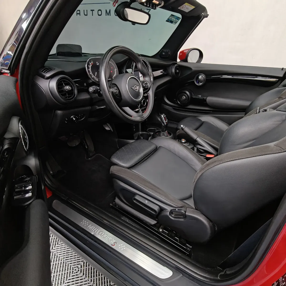 Vista lateral izquierda detallada de los asientos traseros de piel negros en un Mini Cooper S Convertible Hot Chili 2021 seminuevo con capota abierta en Namacar Automotriz.