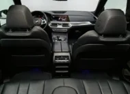 Vista interior en perspectiva trasera central desde la segunda fila que muestra los respaldos delanteros, la consola central trasera y el tablero digital de una SUV premium BMW X5 2021 seminueva con asientos de piel oscuros.