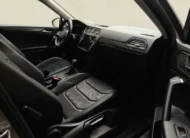 Vista interior desde la puerta del pasajero abierta que muestra la primera fila de asientos deportivos en piel y el tablero ergonómico de una SUV Volkswagen Tiguan 1.4 R-Line 2022 seminueva en ángulo oblicuo derecho.