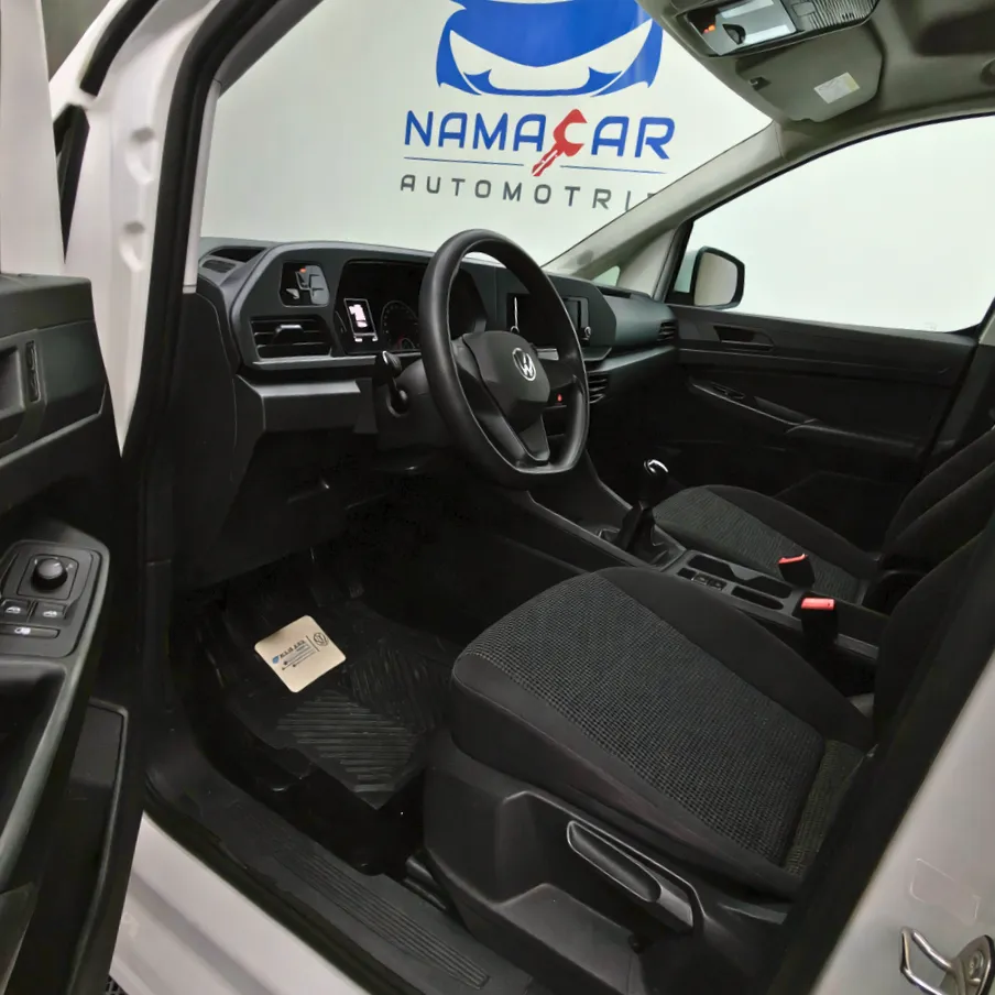 Vista interior desde la puerta del conductor abierta que muestra los asientos delanteros y el tablero de una van de carga Volkswagen Caddy 2.0 Maxi TDI MT 2022 seminueva en ángulo oblicuo izquierdo.