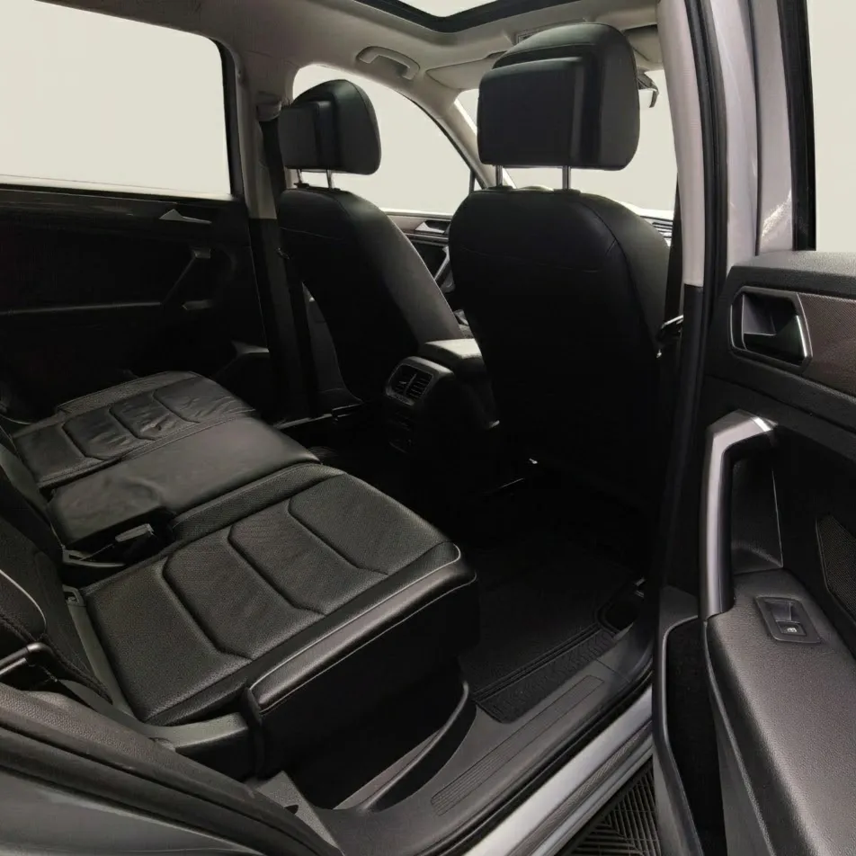 Vista interior desde la puerta trasera derecha abierta que muestra la segunda fila de asientos en piel, el espacio posterior para pasajeros y el techo panorámico de una SUV Volkswagen Tiguan 1.4 R-Line 2022 seminueva en ángulo oblicuo derecho.