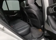 Vista interior desde la puerta trasera derecha abierta que muestra los asientos de piel de la segunda fila, el respaldo del copiloto y el techo panorámico de una SUV premium BMW X5 2021 seminueva en ángulo oblicuo derecho.