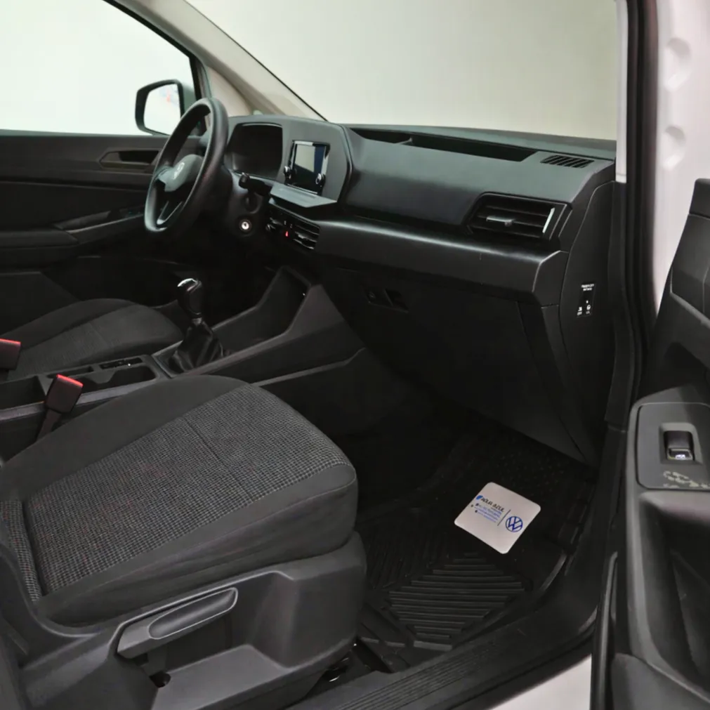Vista interior desde la puerta del pasajero abierta que muestra la cabina delantera, el asiento del acompañante y el tablero de una van de carga Volkswagen Caddy 2.0 Maxi TDI MT 2022 seminueva en ángulo oblicuo derecho.