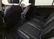 Vista interior desde la puerta trasera izquierda abierta que muestra la segunda fila de asientos en piel, el espacio posterior para pasajeros y los respaldos delanteros de una SUV Volkswagen Tiguan 1.4 R-Line 2022 seminueva en ángulo oblicuo izquierdo.