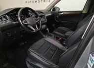 Vista interior desde la puerta del conductor abierta que muestra el asiento de piel del piloto, el volante multifunción y el tablero digital de una SUV Volkswagen Tiguan 1.4 R-Line 2022 seminueva en ángulo oblicuo izquierdo.