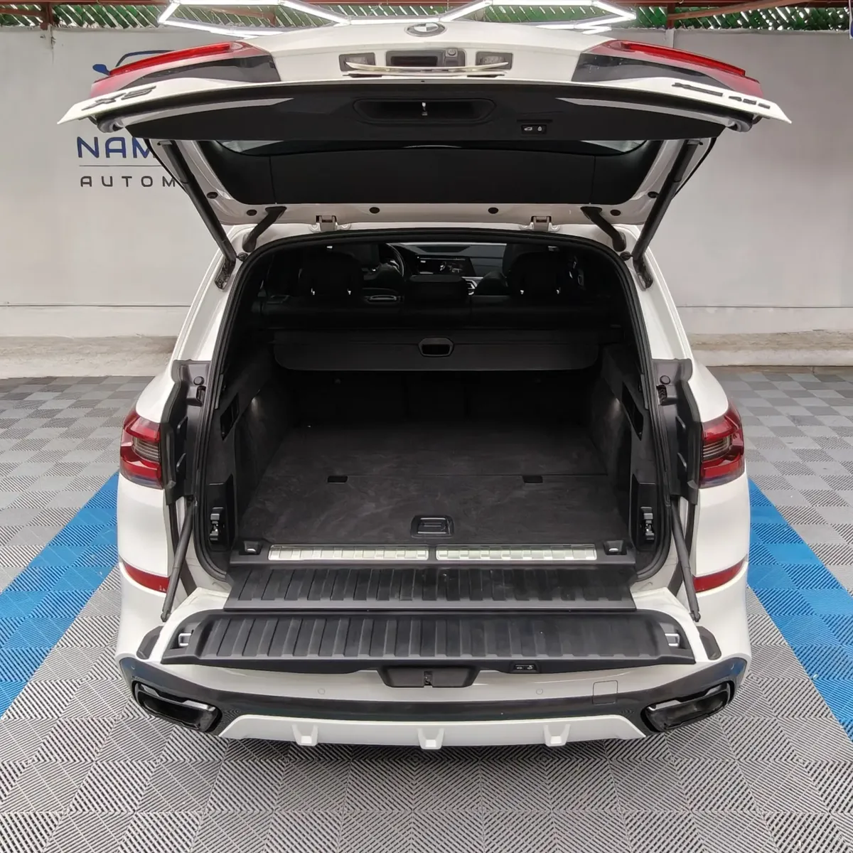 Vista exterior trasera de la amplia cajuela abierta con doble portón de una SUV premium BMW X5 2021 seminueva en color blanco, exhibida en Namacar Automotriz.