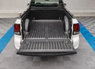 Vista exterior trasera de la batea de carga abierta con recubrimiento plástico protector (bedliner) de una camioneta pick-up Volkswagen Saveiro 1.6 Robust MT año 2025 seminueva en color blanco, en Namacar Automotriz.