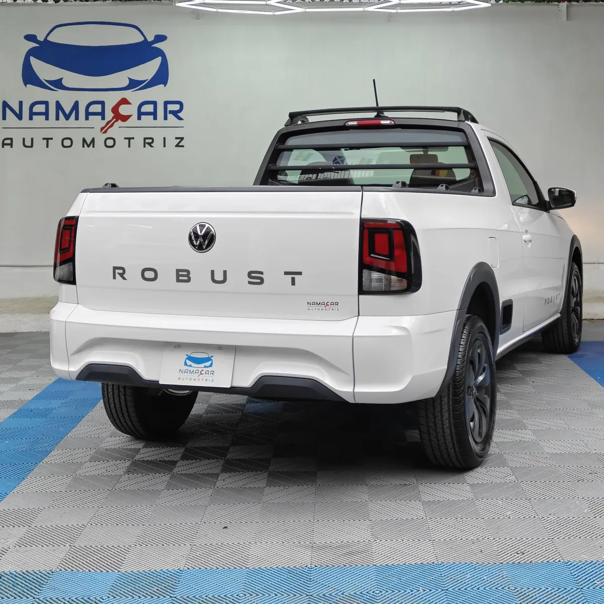 Camioneta pick-up utilitaria Volkswagen Saveiro 1.6 Robust MT año 2025 seminueva en color blanco, vista exterior trasera en ángulo de tres cuartos derecha exhibida en Namacar Automotriz.
