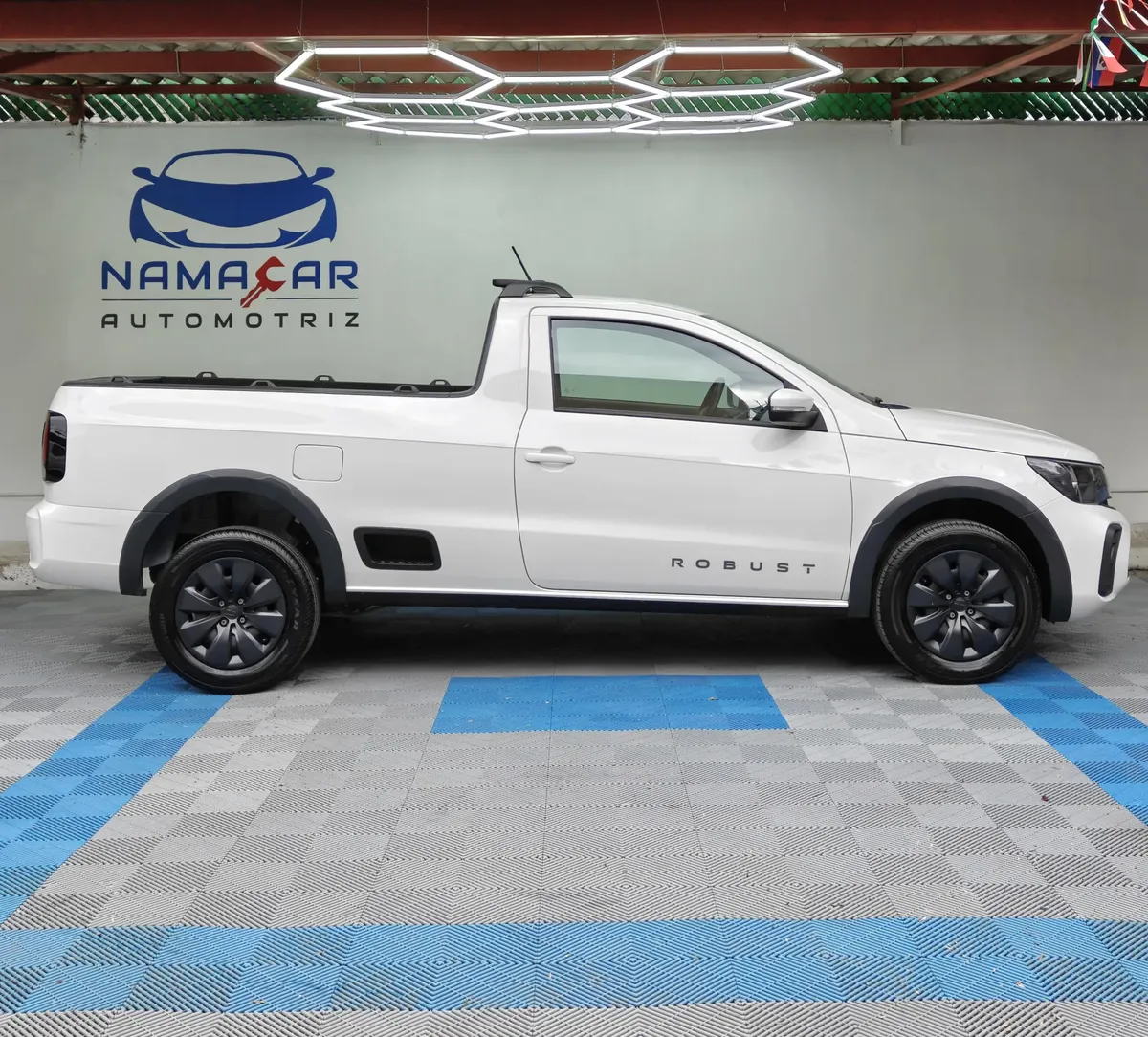 Camioneta pick-up de cabina sencilla Volkswagen Saveiro 1.6 Robust MT año 2025 seminueva en color blanco, vista exterior de perfil lateral derecho completo en el piso de exhibición de Namacar Automotriz.