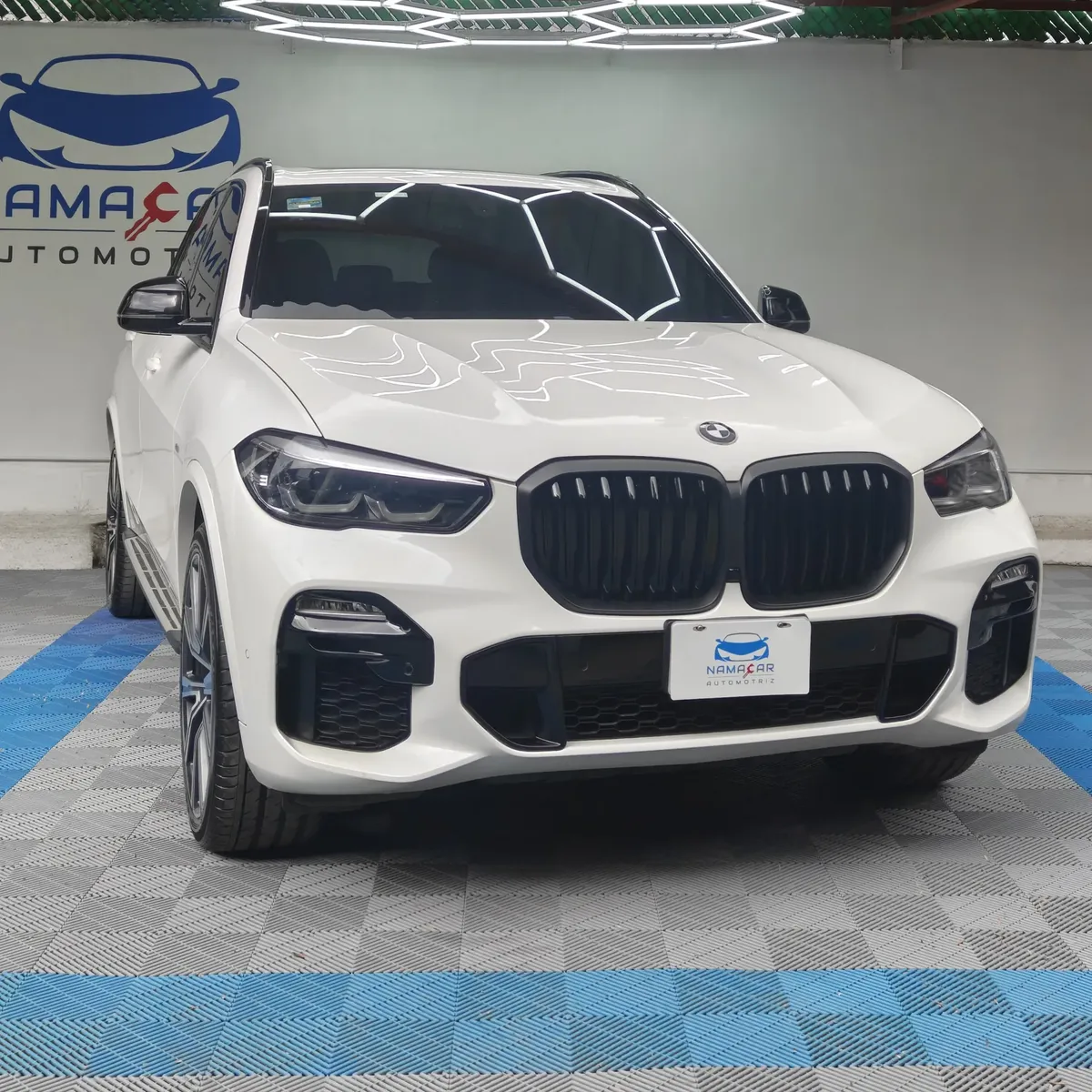SUV híbrida premium BMW X5 2021 seminueva en color blanco, vista exterior frontal en ángulo de tres cuartos derecha exhibida en las instalaciones de Namacar Automotriz