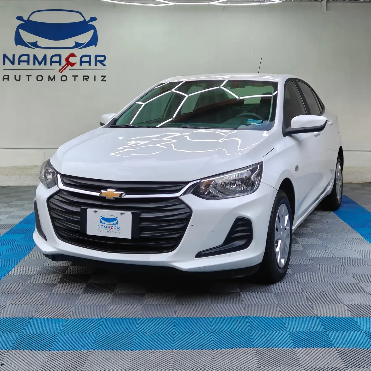 Auto sedán subcompacto Chevrolet Onix 1.3 LS manual año 2024 seminuevo en color blanco, vista exterior frontal en ángulo de tres cuartos izquierda exhibido en Namacar Automotriz.