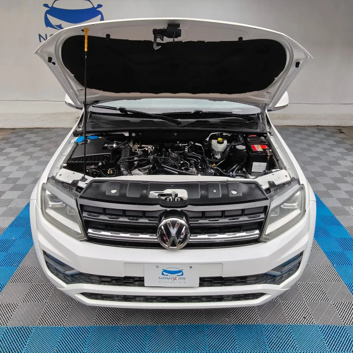 Vista exterior frontal en picada superior con el cofre abierto que muestra el motor 2.0 TDI de una camioneta pickup Volkswagen Amarok 2.0 Highline 4Motion automática año 2018 seminueva en color blanco, en Namacar Automotriz.