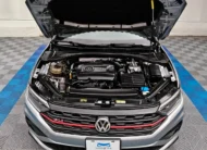 Vista exterior frontal en picada superior con el cofre abierto que muestra el motor 2.0 Turbo de un auto sedán deportivo Volkswagen Jetta 2.0 GLI DSG automático año 2021 seminuevo en color gris plata, en Namacar Automotriz.