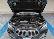 Camioneta SUV de lujo BMW X1 2.0 sDrive20i sDrive 20iA X Line transmisión automática año 2022 seminueva en color negro, vista exterior frontal centrada con el cofre abierto exhibiendo el compartimento del motor TwinPower Turbo 2.0 L en Namacar Automotriz.