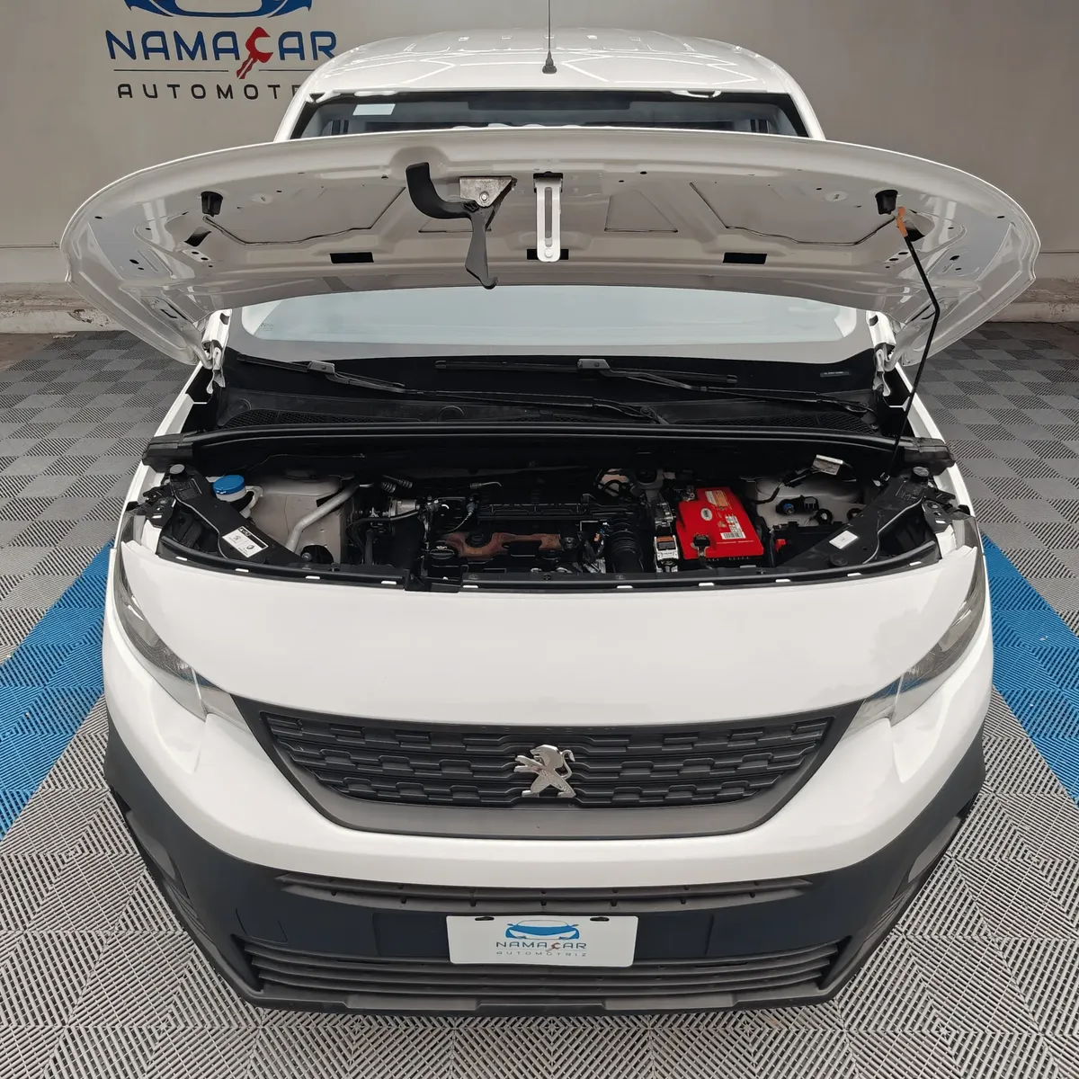 Camioneta de carga comercial Peugeot Partner 1.6 HDi Maxi transmisión manual año 2021 seminueva en color blanco, vista exterior frontal centrada con el cofre abierto exhibiendo el compartimento del motor Diésel 1.6 L HDi en Namacar Automotriz.