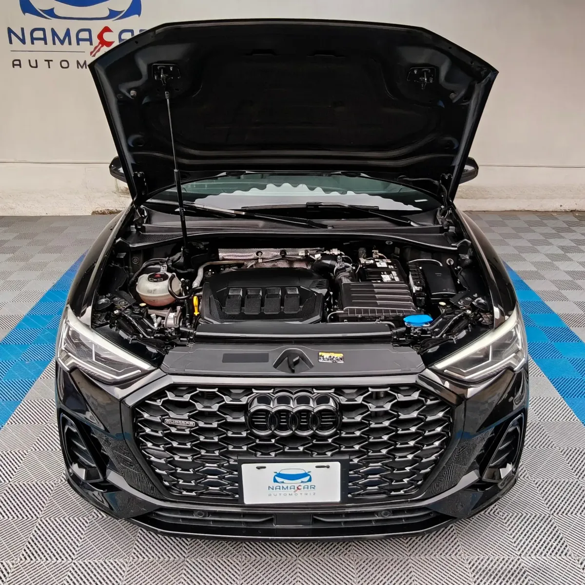 Camioneta SUV coupé de lujo Audi Q3 Sportback 2.0 S Line 180 Hp transmisión DSG automática año 2022 seminueva en color negro, vista exterior frontal centrada con el cofre abierto exhibiendo el compartimento del motor 2.0 L TFSI en Namacar Automotriz.