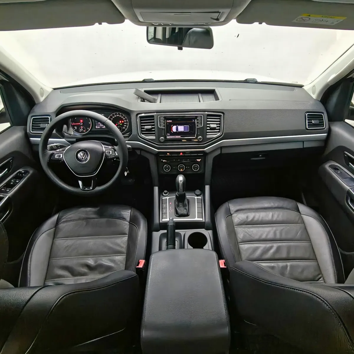 Vista interior cenital desde arriba que muestra la cabina, tablero, volante multifunción, consola central y asientos delanteros de piel negra de una camioneta pickup Volkswagen Amarok 2.0 Highline 4Motion automática año 2018 seminueva.