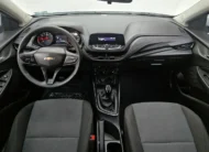Vista interior cenital desde arriba que muestra la cabina, el tablero, el sistema de audio, el volante multifunción y los asientos delanteros en tela de un auto sedán Chevrolet Onix 1.3 LS manual año 2024 seminuevo.