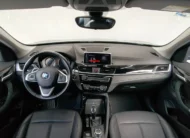 Vista interior panóramica desde los asientos traseros que muestra la cabina delantera completa, el tablero de instrumentos, la pantalla de infoentretenimiento, el volante multifunción y los asientos de piel negros de una camioneta SUV de lujo BMW X1 2.0 sDrive20i sDrive 20iA X Line transmisión automática año 2022 seminueva.