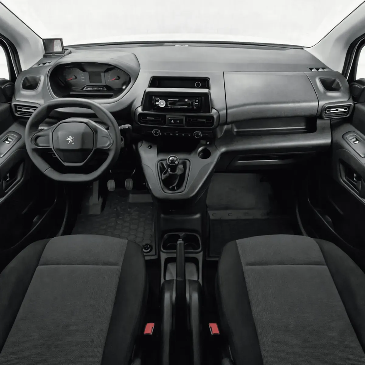 Vista interior panorámica desde la parte trasera que muestra la cabina delantera completa, el tablero ergonómico i-Cockpit, el volante, la palanca de velocidades en consola y los asientos de tela oscuros de una camioneta comercial Peugeot Partner 1.6 HDi Maxi transmisión manual año 2021 seminueva.