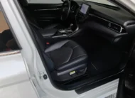 Vista interior desde la puerta del copiloto abierta que muestra el asiento de piel, la guantera, el tablero y la consola central de un auto sedán híbrido Toyota Camry 2.5 HEV XLE año 2024 seminuevo en ángulo oblicuo derecho.