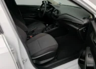 Vista interior desde la puerta del copiloto abierta que muestra el asiento en tela del acompañante, la guantera, el tablero y la consola central de un auto sedán Chevrolet Onix 1.3 LS manual año 2024 seminuevo en ángulo oblicuo derecho.