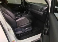 Vista interior desde la puerta del copiloto abierta que muestra el asiento de piel, la guantera, el tablero y la consola central de una camioneta pickup Volkswagen Amarok 2.0 Highline 4Motion automática año 2018 seminueva en ángulo oblicuo derecho.