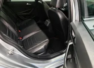 Vista interior desde la puerta trasera derecha abierta que muestra la banca de asientos posteriores tapizados en piel negra y la zona de pasajeros de un auto sedán Volkswagen Jetta 2.