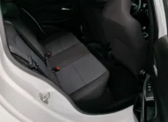 Vista interior desde la puerta trasera derecha abierta que muestra la banca de asientos posteriores en tela gris y el espacio para piernas de un auto sedán Chevrolet Onix 1.3 LS manual año 2024 seminuevo en ángulo oblicuo derecho.