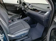 Vista interior desde la puerta del copiloto abierta que muestra el asiento delantero derecho en piel negra con ajustes eléctricos, la consola central, la pantalla táctil y el tablero de una camioneta SUV de lujo BMW X1 2.0 sDrive20i sDrive 20iA X Line transmisión automática año 2022 seminueva en ángulo oblicuo derecho.