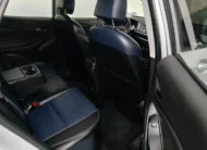Vista interior desde la puerta trasera derecha abierta que muestra la banca de asientos posteriores tapizados en piel bitono azul y negro, el descansabrazos central desplegado con portavasos y el espacio para piernas de una camioneta SUV Chevrolet Tracker 1.2 Premier Turbo transmisión automática año 2023 seminueva en ángulo oblicuo derecho.