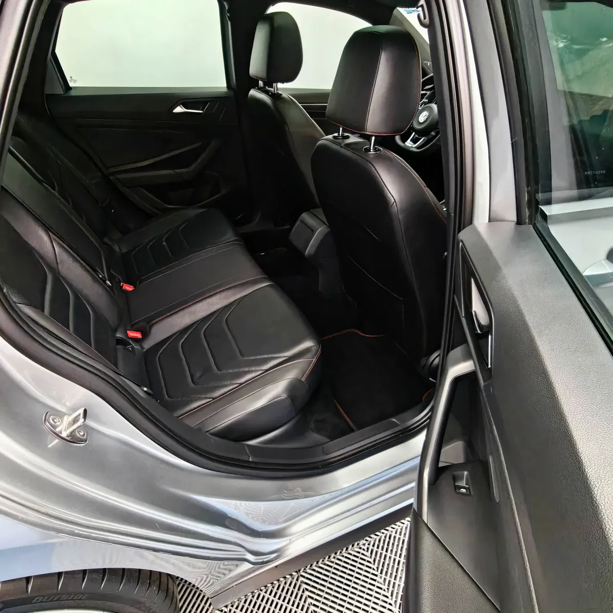 Vista interior desde la puerta trasera derecha abierta que muestra la banca de asientos posteriores tapizados en piel negra y la zona de pasajeros de un auto sedán Volkswagen Jetta 2.