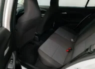 Vista interior desde la puerta trasera izquierda abierta que muestra la banca de asientos posteriores en tela gris, el espacio para piernas y los respaldos delanteros de un auto sedán Chevrolet Onix 1.3 LS manual año 2024 seminuevo en ángulo oblicuo izquierdo.