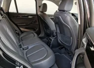 Vista interior desde la puerta trasera derecha abierta que muestra la banca de asientos posteriores tapizados en piel negra, el espacio para piernas, las salidas de aire acondicionado traseras y el respaldo del asiento del copiloto de una camioneta SUV de lujo BMW X1 2.0 sDrive20i sDrive 20iA X Line transmisión automática año 2022 seminueva en ángulo oblicuo derecho.