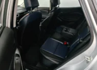 Vista interior desde la puerta trasera izquierda abierta que expone la banca de asientos posteriores tapizados en piel bitono azul y negro, el descansabrazos central abatible con portavasos y el amplio habitáculo de una camioneta SUV Chevrolet Tracker 1.2 Premier Turbo transmisión automática año 2023 seminueva en ángulo oblicuo izquierdo.