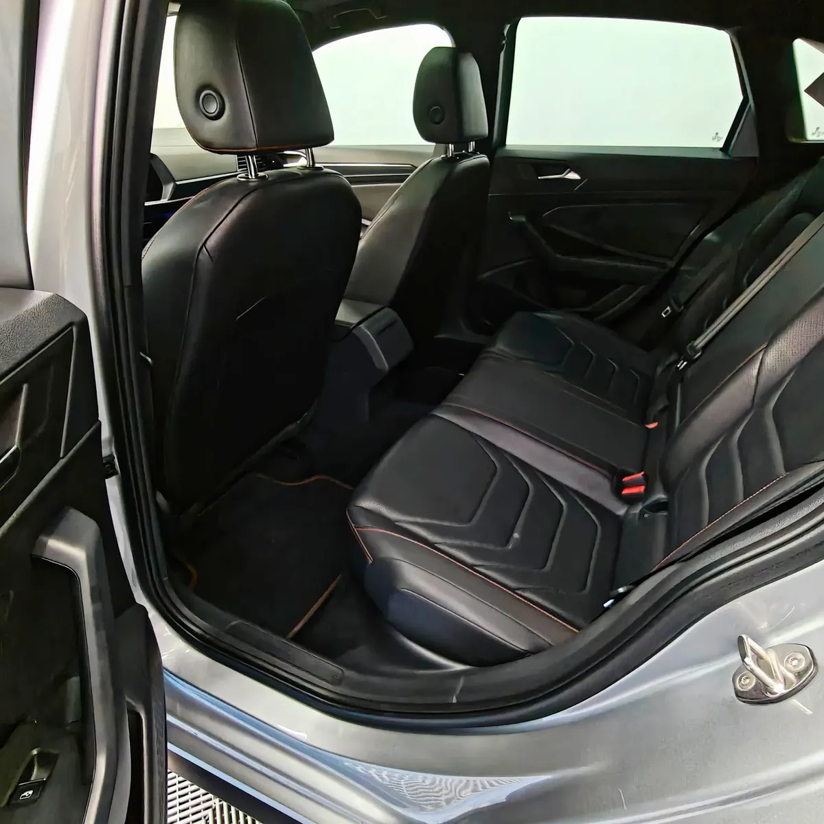 Vista interior desde la puerta trasera izquierda abierta que muestra la banca de asientos posteriores tapizados en piel negra y el habitáculo de un auto sedán Volkswagen Jetta 2.0 GLI DSG automático año 2021 seminuevo en ángulo oblicuo izquierdo.