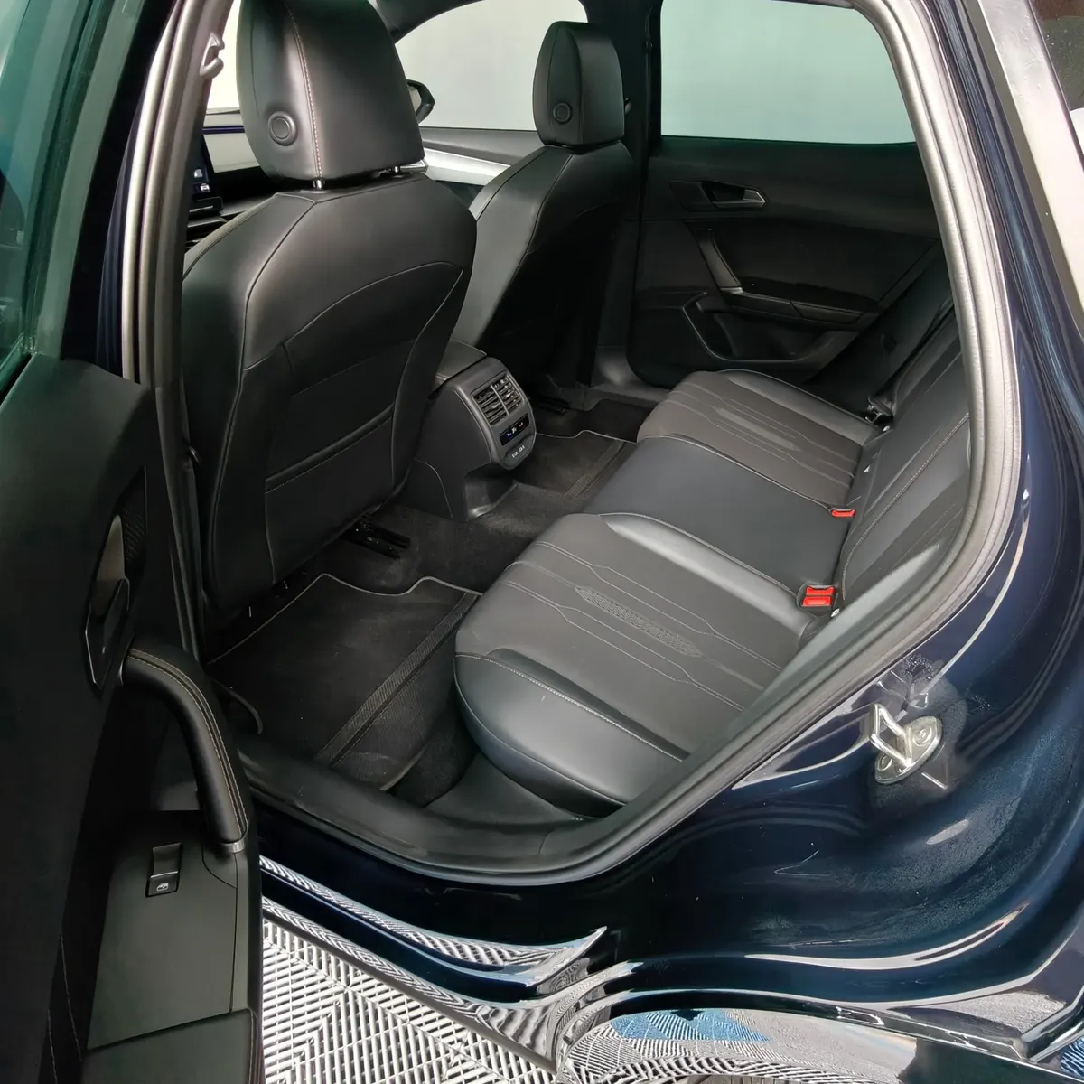 Vista interior desde la puerta trasera izquierda abierta que muestra la banca de asientos posteriores en piel y tela, el espacio para piernas y el panel de puerta de una SUV Crossover deportiva Cupra Formentor 2.0 Mid 190 HP 2WD DSG7 año 2022 seminueva en ángulo oblicuo izquierdo.