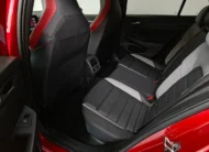 Vista interior desde la puerta trasera izquierda abierta que muestra la banca de asientos posteriores bitono, el espacio para piernas, las salidas de aire acondicionado y el respaldo del asiento del conductor de un hatchback deportivo Volkswagen Golf GTI 2.0 241 HP DSG7 año 2024 seminuevo en ángulo oblicuo izquierdo.