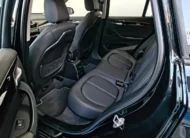 Vista interior desde la puerta trasera izquierda abierta que muestra la banca de asientos posteriores tapizados en piel negra, el espacio para piernas, las salidas de aire acondicionado y el respaldo del asiento del conductor de una camioneta SUV de lujo BMW X1 2.0 sDrive20i sDrive 20iA X Line transmisión automática año 2022 seminueva en ángulo oblicuo izquierdo.