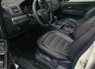 Vista interior desde la puerta del conductor abierta que muestra el asiento del piloto, volante multifunción, cuadro de instrumentos y tablero de una camioneta pickup Volkswagen Amarok 2.0 Highline 4Motion automática año 2018 seminueva en ángulo oblicuo izquierdo.