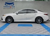 Auto sedán híbrido Toyota Camry 2.5 HEV XLE año 2024 seminuevo en color blanco, vista exterior de perfil lateral izquierdo completo exhibido en Namacar Automotriz.