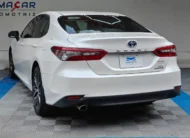 Auto sedán híbrido Toyota Camry 2.5 HEV XLE año 2024 seminuevo en color blanco, vista exterior trasera en ángulo de tres cuartos izquierda exhibido en Namacar Automotriz.