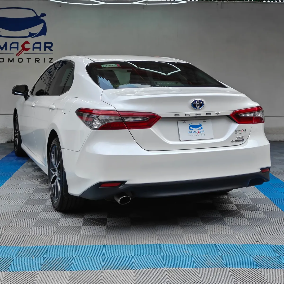 Auto sedán híbrido Toyota Camry 2.5 HEV XLE año 2024 seminuevo en color blanco, vista exterior trasera en ángulo de tres cuartos izquierda exhibido en Namacar Automotriz.