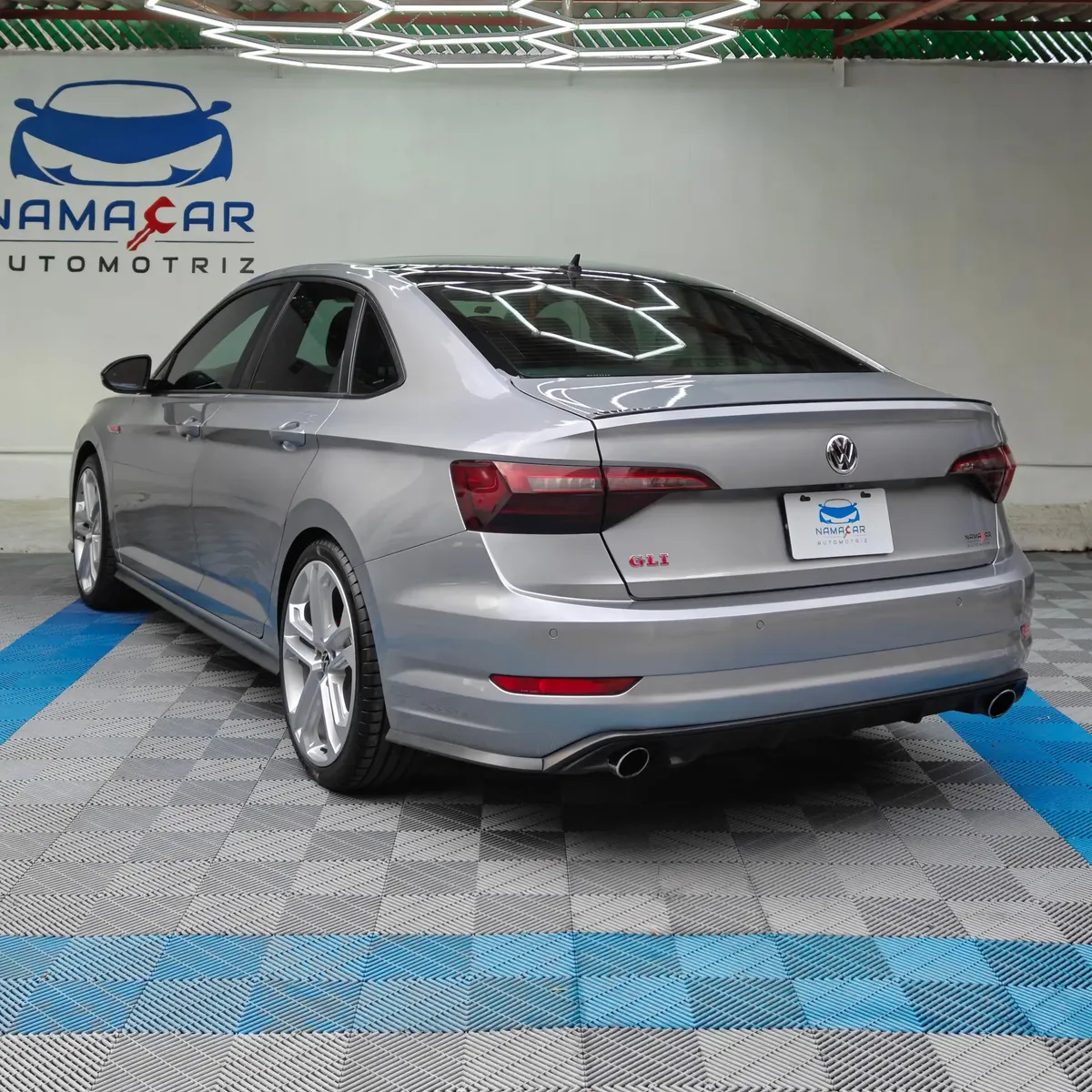 Auto sedán deportivo Volkswagen Jetta 2.0 GLI DSG automático año 2021 seminuevo en color gris plata, vista exterior trasera en ángulo de tres cuartos izquierda exhibido en Namacar Automotriz.