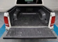 Vista exterior trasera de la batea de carga abierta que muestra el recubrimiento bedliner protector y el espacio de carga de una camioneta pickup Volkswagen Amarok 2.0 Highline 4Motion automática año 2018 seminueva en color blanco, en Namacar Automotriz.