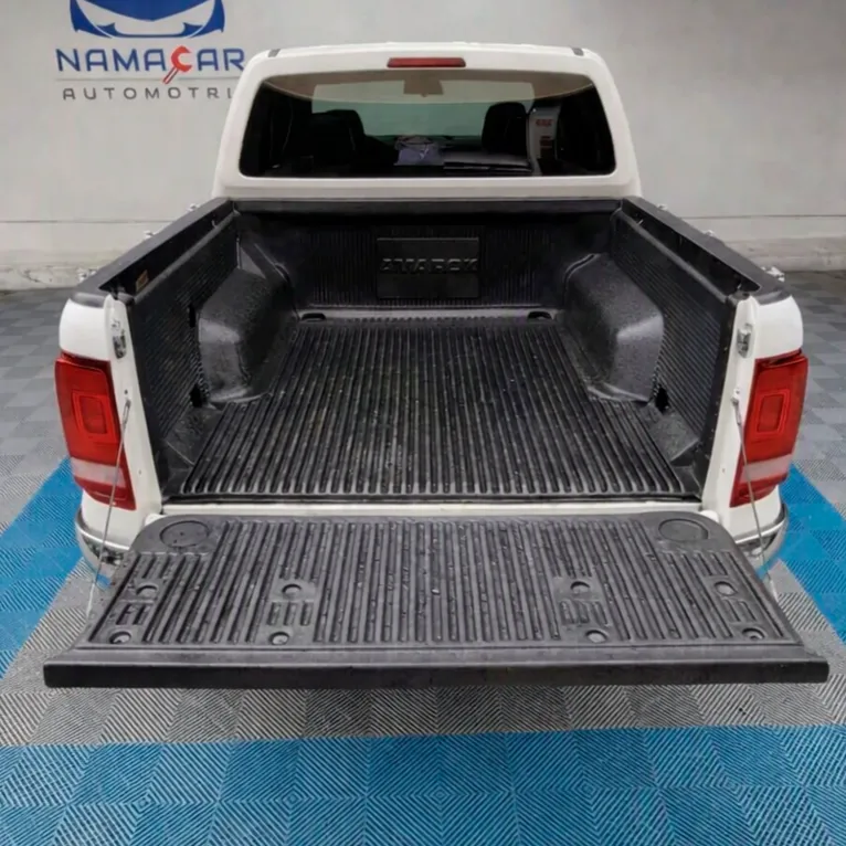 Vista exterior trasera de la batea de carga abierta que muestra el recubrimiento bedliner protector y el espacio de carga de una camioneta pickup Volkswagen Amarok 2.0 Highline 4Motion automática año 2018 seminueva en color blanco, en Namacar Automotriz.