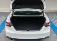 Vista exterior trasera directa con la cajuela abierta que muestra el amplio espacio del compartimento de equipaje de un auto sedán híbrido Toyota Camry 2.5 HEV XLE año 2024 seminuevo en color blanco, en Namacar Automotriz.