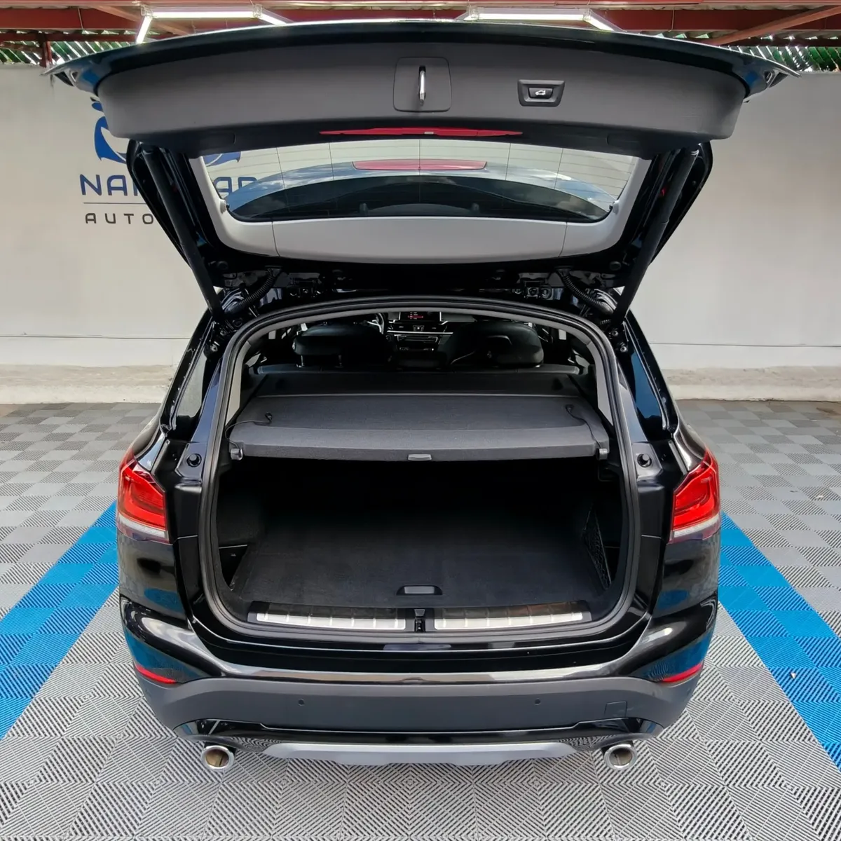 Camioneta SUV de lujo BMW X1 2.0 sDrive20i sDrive 20iA X Line transmisión automática año 2022 seminueva en color negro, vista exterior trasera centrada con el portón de la cajuela abierto mostrando el área de carga posterior exhibida en Namacar Automotriz.
